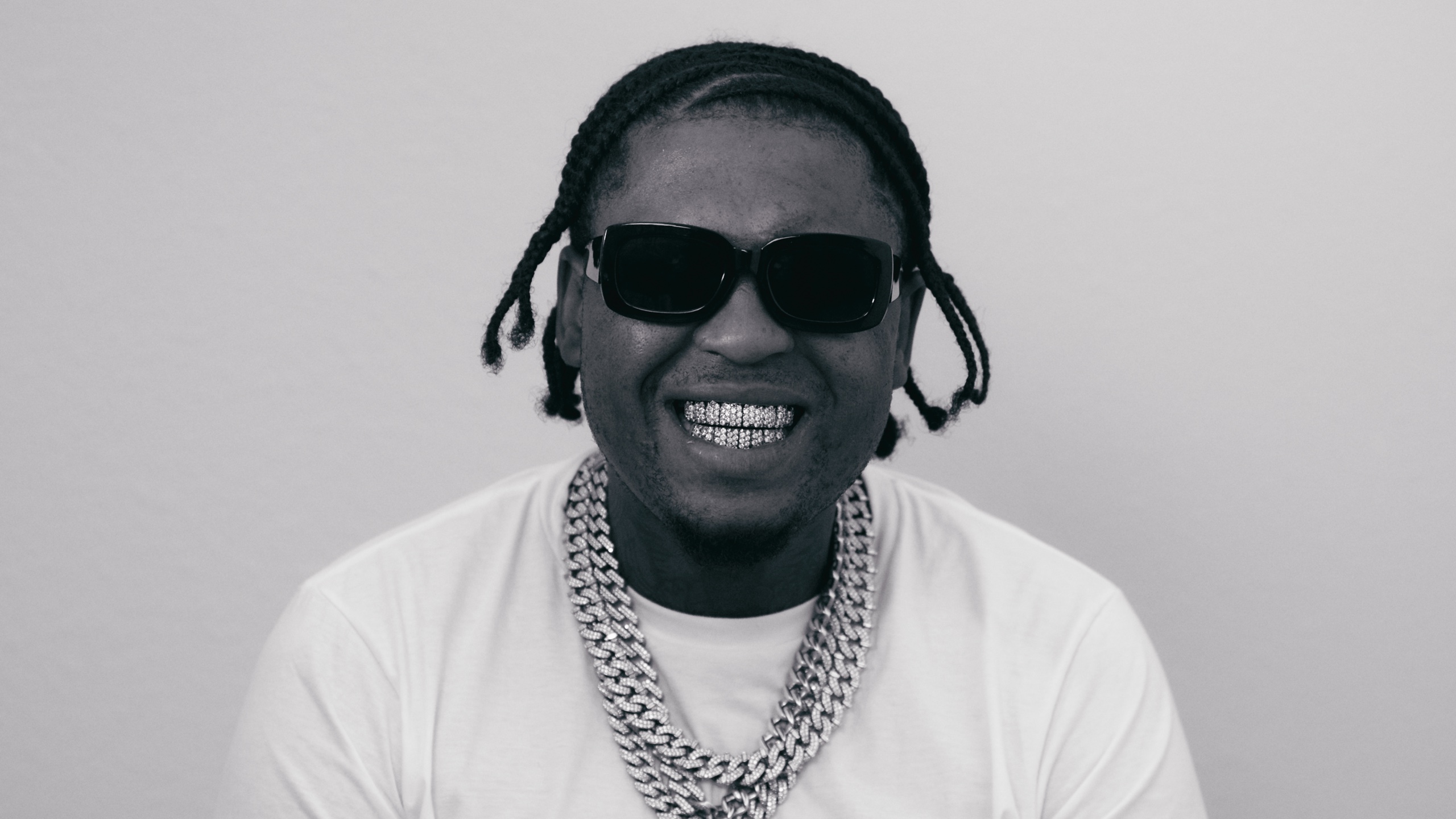 Black-and-white close-up of Loco Los wearing sunglasses and diamond jewelry