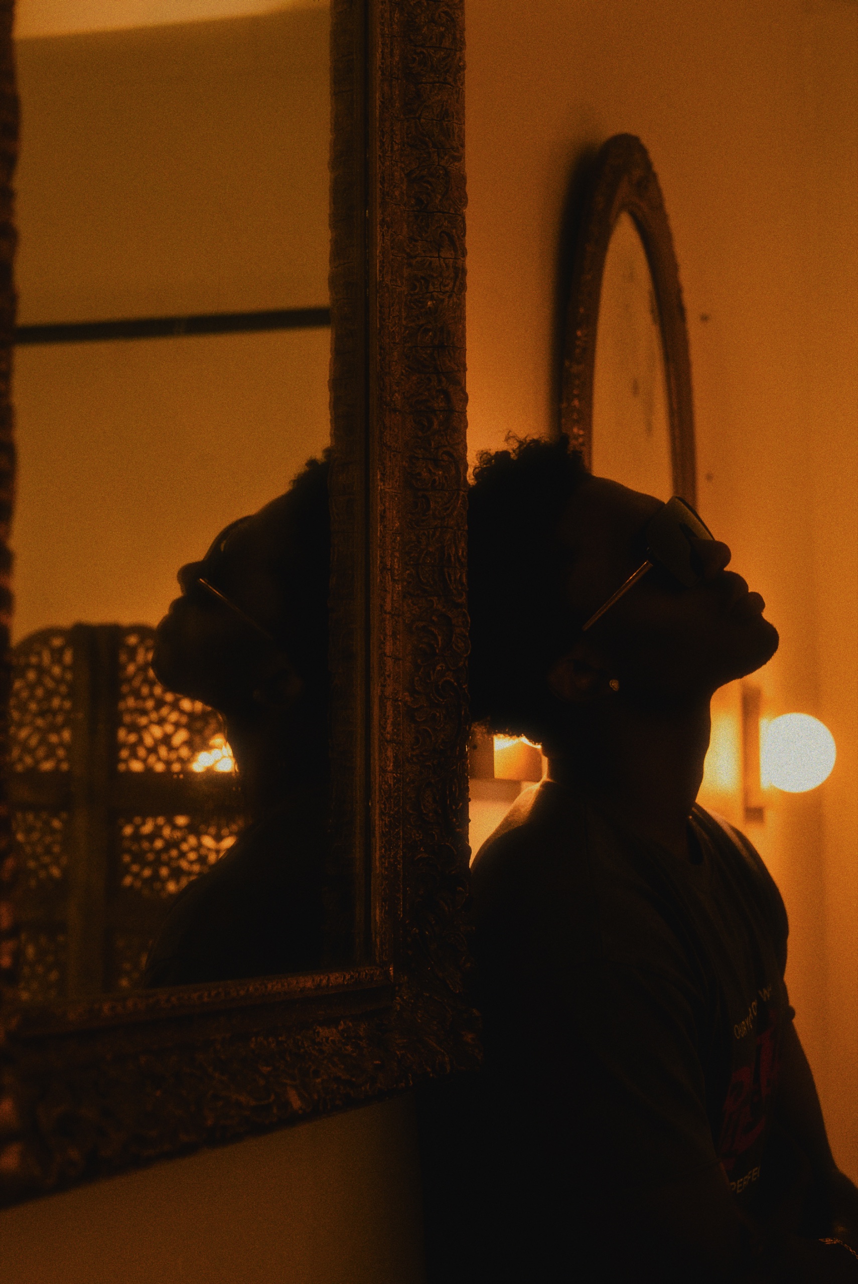 NIGE photographed in warm light beside an ornate mirror